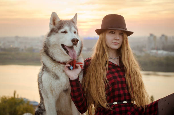 istock Young woman with husky at sunset overlooking cityscape 2201953983