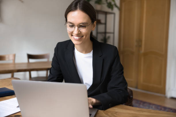 istock Young woman working on laptop is seated at desk 2201954125