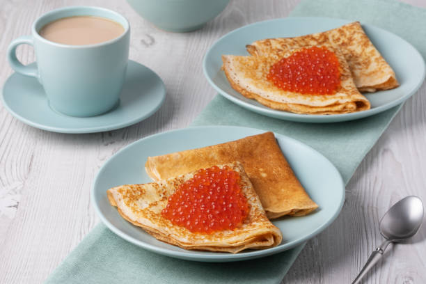 istock Savory crepes filled with fresh orange fish roe served on a light blue plate at a cozy breakfast table 2201954850