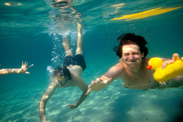 istock Laughing friends splash into the ocean depths 2201956080