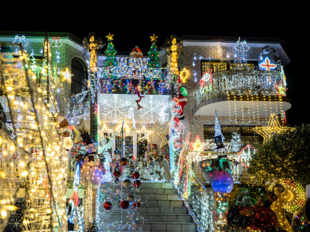 Colorful Christmas lights decorate a two-story house, yard and fence with a bright snowman and festive figures, creating a joyful holiday scene full of warmth and celebration.Brooklyn, NYC, USA