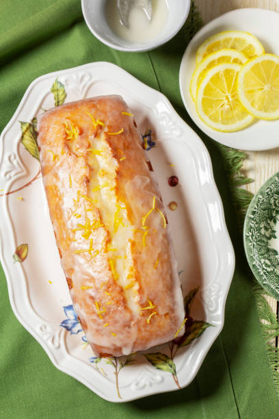 Aromatic lemon cake, covered with sugar icing and sprinkled with zest, served with tea. Breakfast of lemon pie with tea on a light background, rustic style.