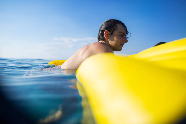 Man enjoying on a yellow mattress in the sea