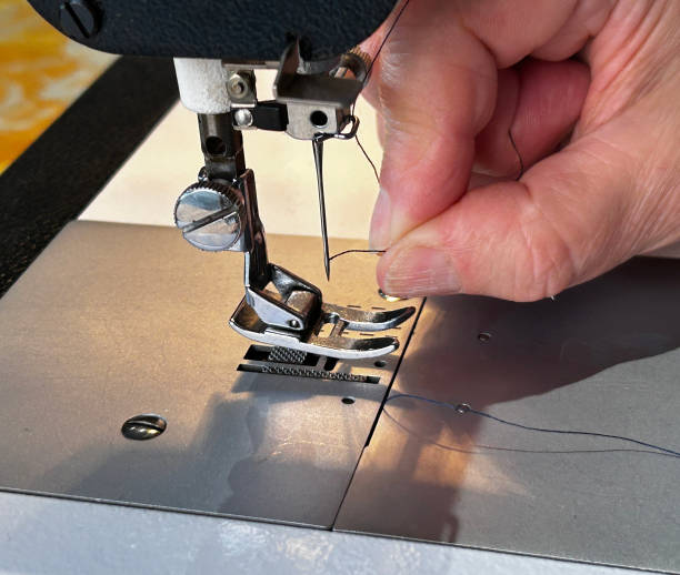 istock Close-up of seamstress threading needle on sewing machine, preparing for dressmaking or tailoring work 2201961313