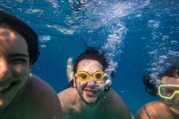 istock A woman and two young men dive into the ocean, gliding toward the camera 2201961327