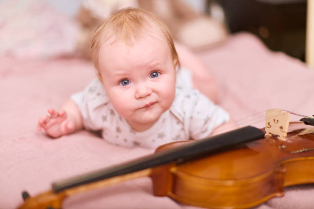 istock Curious baby girl with violin on soft pink bedding 2201965066