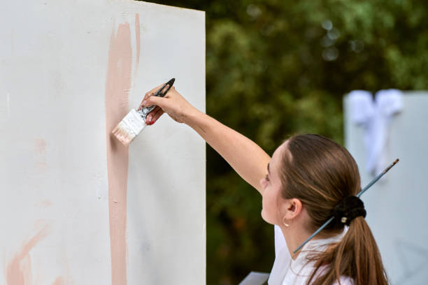istock Young artist painting mural outdoors with focused expression 2201965077