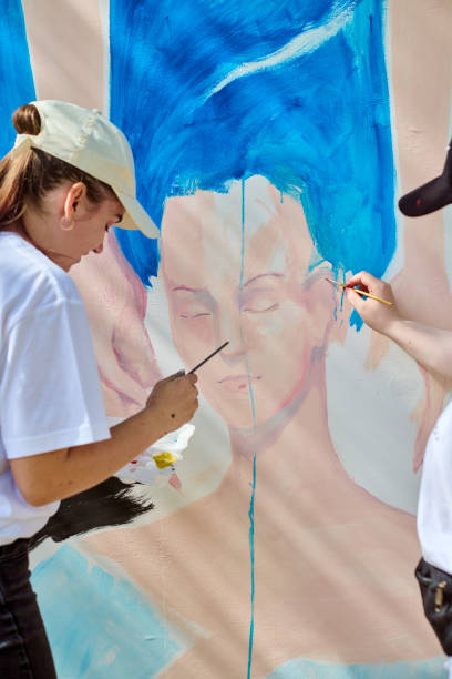 istock Two young women collaborating on large wall art 2201965120