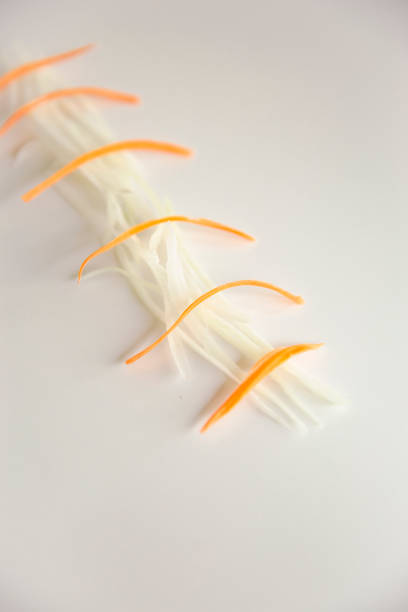 Thinly sliced julienne papaya and carrot arranged on a white background, Fresh shredded ingredients for Thai green papaya salad, Minimalist food styling concept