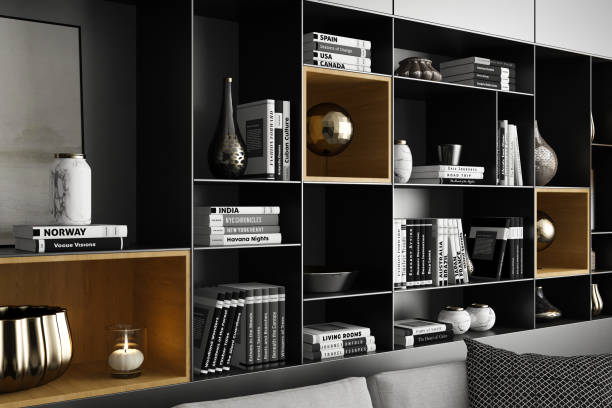 A beautifully designed modern interior living room featuring a spacious layout with a large portal window leading to a patio. The room showcases a cozy yet luxurious aesthetic with black-and-white tones, a light grey fabric sofa, and stylish seating arrangements. A wall of shelves adorned with books and household decorations adds sophistication, while a large carpet and coffee table complete the elegant ambiance. Ideal for renovation projects, architecture firms, real estate listings, designer portfolios, rentals, and interior design inspiration.