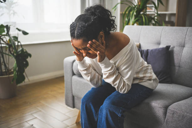 istock Distraught black woman sitting on a sofa at home 2201979337