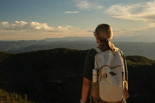 istock Woman with a backpack on her back on top of a mountain 2201981850