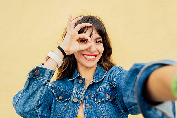 istock Young woman making ok sign taking selfie with yellow background 2201982638