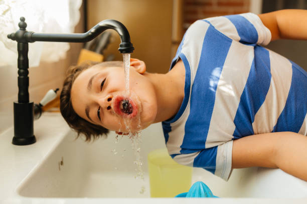 istock Boy Playfully Drinking Water from a Kitchen Faucet 2201982690