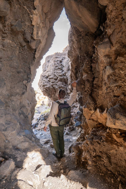istock Hiker Exploring Rocky Cave on a Sunny Day 2201984044