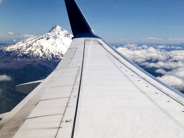 Airplane wing in foreground and Mt Hood in background with blue sky and clouds