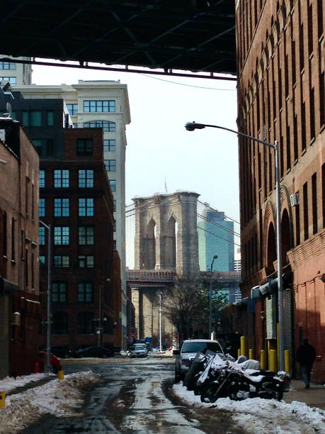 istock low angle Brooklyn Bridge on a snowy winter day visible between buildings in DUMBO neighborhood of Brooklyn, NY 2201984542