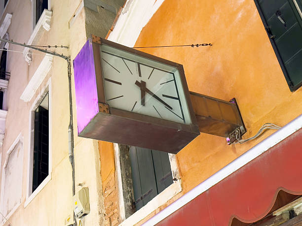 Vintage wall-mounted metal clock on colorful building exterior, lifestyle