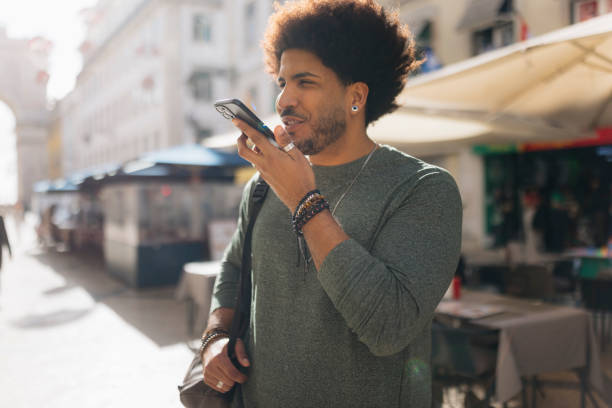 istock Young man sending a voice message walking down the street 2201986564