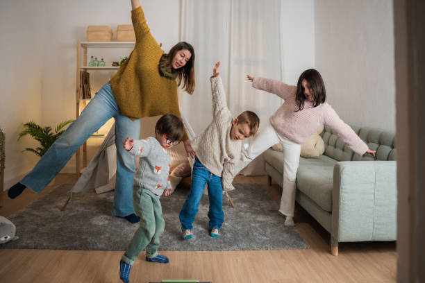 istock Mother and children having fun while balancing in living room 2201988359