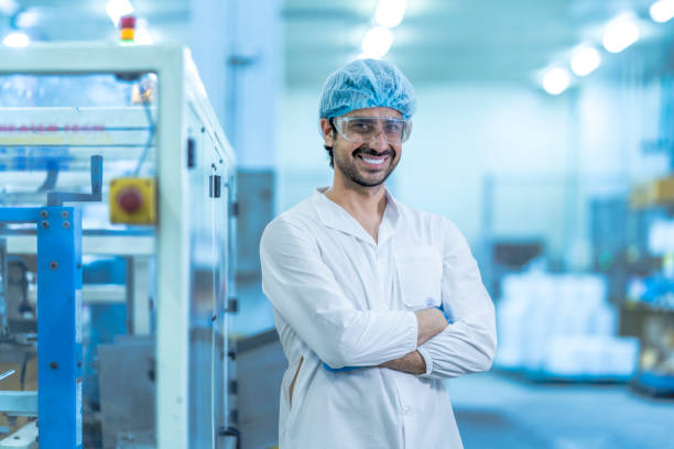 istock A confident food processing supervisor in protective gear, standing with arms crossed next to machinery in a factory, symbolizing leadership, quality assurance, and operational safety. 2201991214