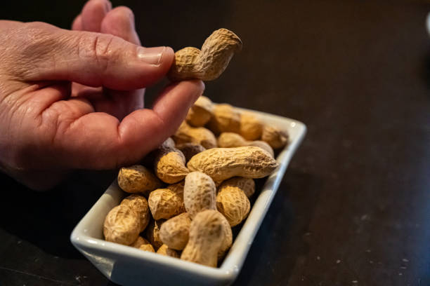 istock Mano cogiendo un cacahuete de aperitivo de un recipiente en la mesa de un bar, 2201991932