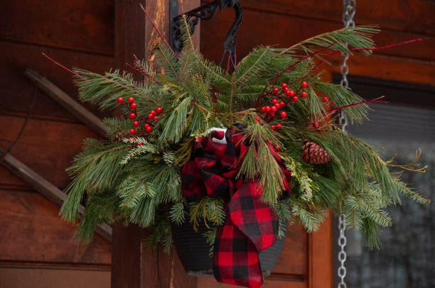 A creative decorative arrangement featuring pine foliage, vibrant red berries, and a festive plaid bow. Perfect for celebrating the holiday season with rustic charm and cozy winter vibes.