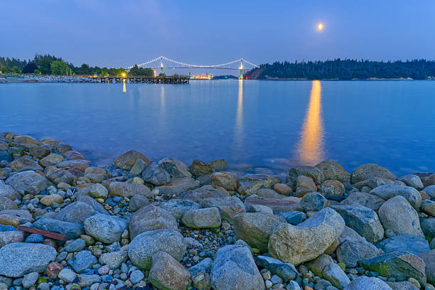 View of Lions Gate Bridge at moonrise as seen from West Vancouver from Burrard Inlet, British Columbia