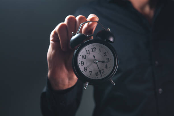 istock businessman hand holding clock on black background, time management concept 2202002505