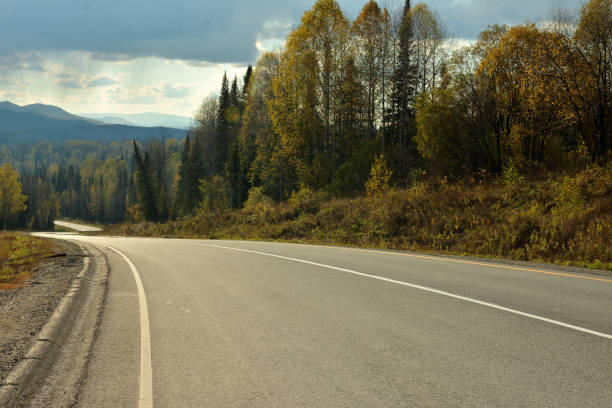 istock A winding asphalt road descends from a mountain into a valley through dense forest on a cloudy autumn day towards the beginning of rain. 2202004377
