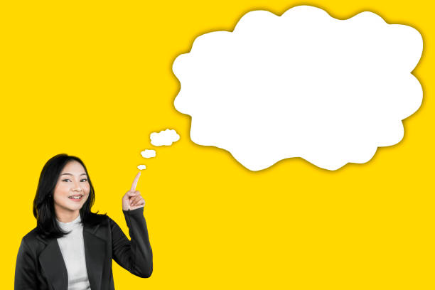 istock Smiling Businesswoman Pointing at Blank Thought Bubble on Yellow Background 2202005181