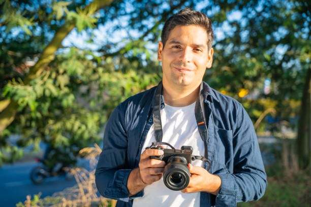 istock A young man holding a camera is surrounded by beautiful nature in this captivating scene 2202006690