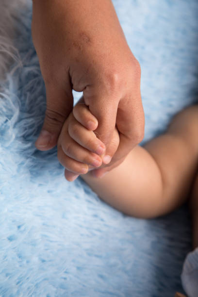 istock Tiny newborn baby human hands and fingers 2202007198