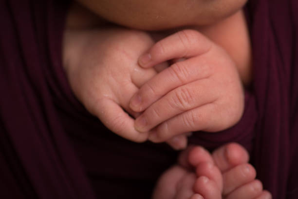 istock Tiny newborn baby human hands and fingers 2202007405