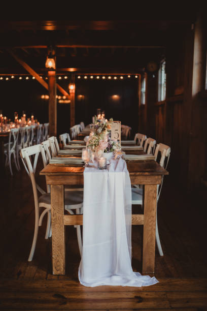 istock Barn wedding reception table with sheer fabric tablecloth and flower arrangement 2202007556
