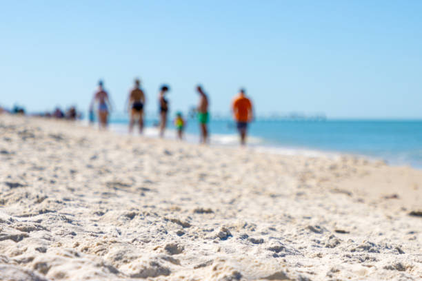 A defocused family with parents and a child vacationing on a sandy beach near the ocean water.