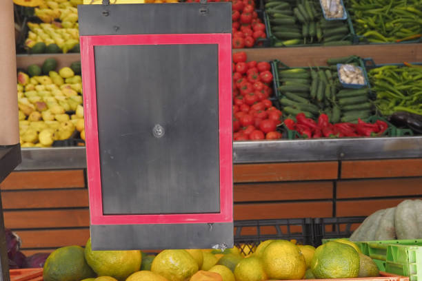 A colorful display of fresh vegetables with a blank sign for pricing or labeling