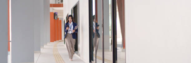 istock Young Asian businesswoman walking outdoors while checking her smartphone with a focused expression 2202014420