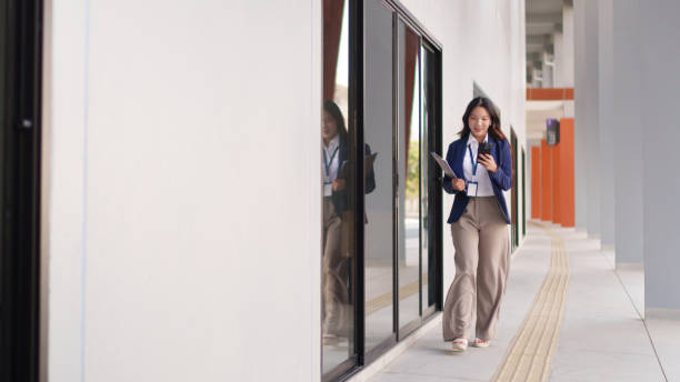 istock Young Asian businesswoman walking outdoors while checking her smartphone with a focused expression 2202014433