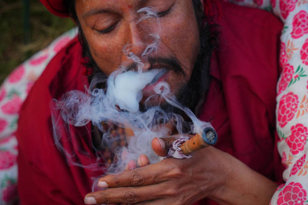 Sadhu smokes marijuana using a traditional chillum at the premises of the Doleswor temple during the Maha Shivaratri Festival in Bhaktapur, Nepal.