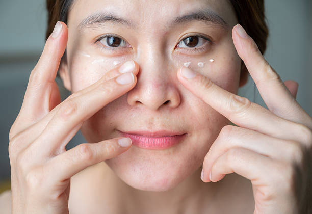 istock Asian woman applying anti aging cream on her under eyes. 2202019665