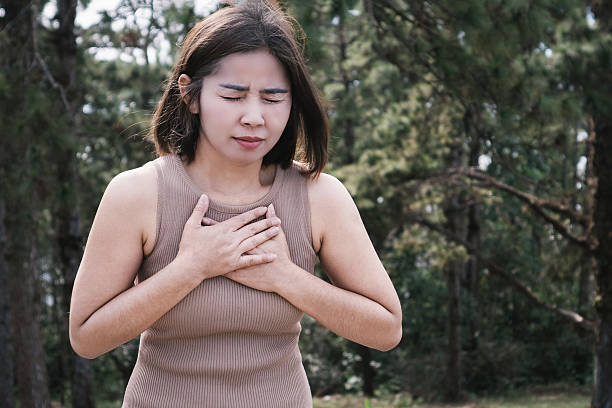 istock Asian woman experiencing chest pain while walking outdoors, feeling discomfort due to symptoms of heart disease, heart attack, or a panic attack 2202019772