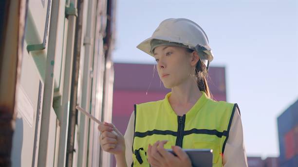 istock Female engineer or supervisor working to logistic business, check container maintenance, preparation container for loading system to cargo freight ship for import and export in loading yard. Concept of logistics business, transportation. 2202020488