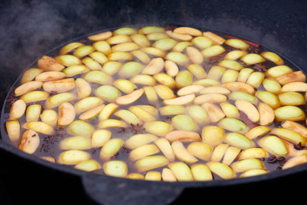 A pan of apples is boiling in a pot. The apples are sliced and are floating in the water