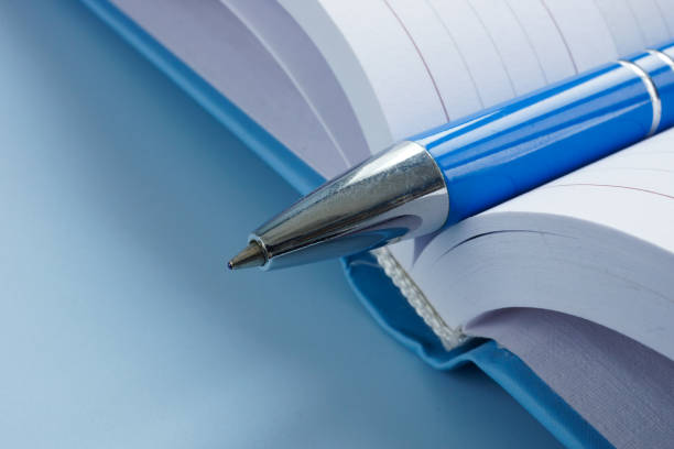 istock Close-up of a pen in an open notebook. Creativity and planning. 2202025477
