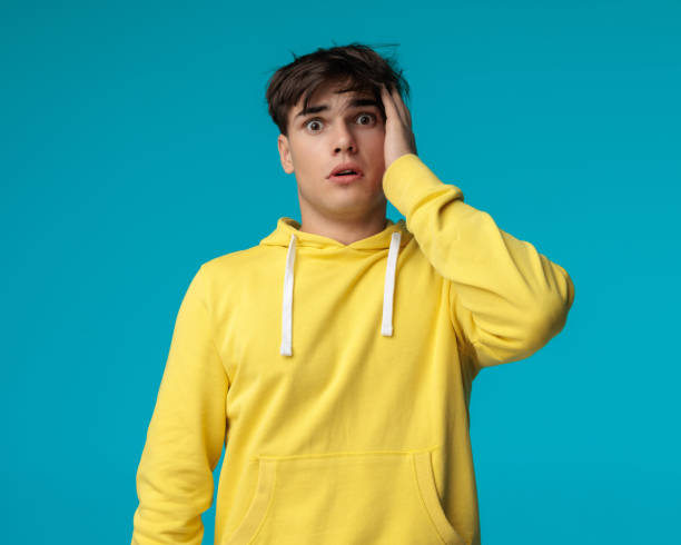 istock attractive young man holding his head is looking astonished 2202027456