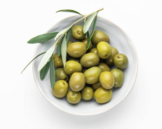 istock Green olives with olive branch resting in a bowl on white background 2202029353