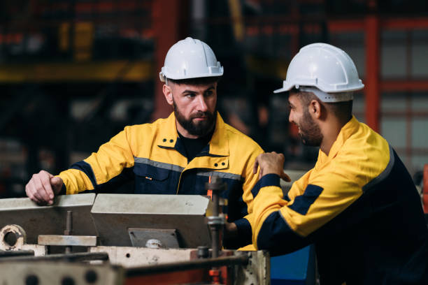 istock Worker inspecting factory machines, a technician working with metal sheets, and a foreman checking materials or equipment. 2202030265