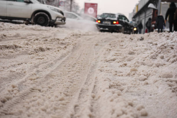 a snowy street with tracks left by car tires.