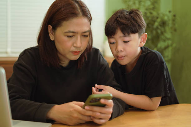 istock ​Boy is looking at a mobile phone with his mother. 2202031501